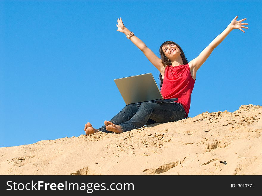 The joyful young woman with a computer on sand. The joyful young woman with a computer on sand