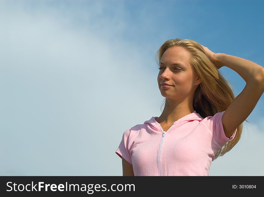 The young beautiful woman reflects on a background of blue sky. The young beautiful woman reflects on a background of blue sky