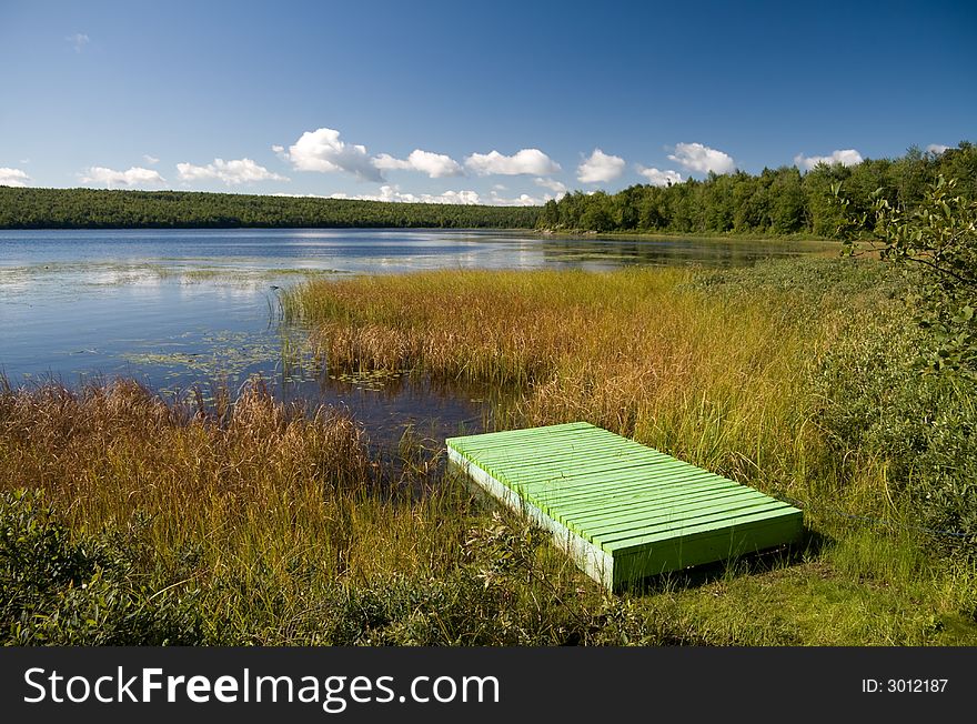 A green wooden pier next to a lake in central Quebec. A green wooden pier next to a lake in central Quebec.