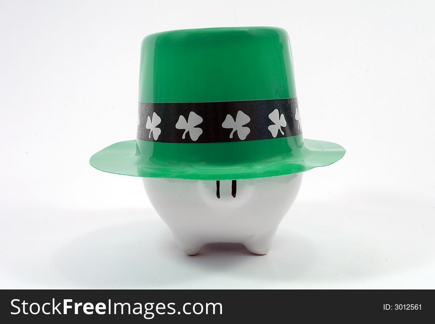 White piggy bank wearing a Saint Patrick's Day hat. Photographed on a white fabric background. White piggy bank wearing a Saint Patrick's Day hat. Photographed on a white fabric background.