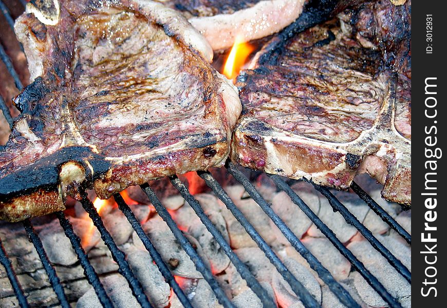 Grilling the T-Bone Steak, with flame and charcoal, nearly done. Grilling the T-Bone Steak, with flame and charcoal, nearly done.