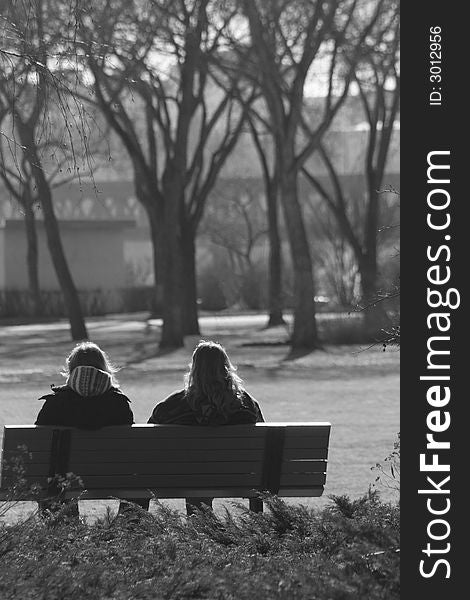 Black and white portrait of two woman enjoying a park from a bench. Black and white portrait of two woman enjoying a park from a bench.