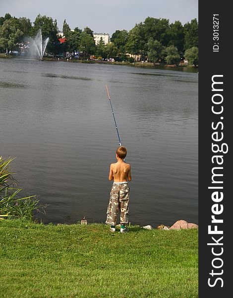 Fishing time... boy on a lake,

background fountain, trees and city