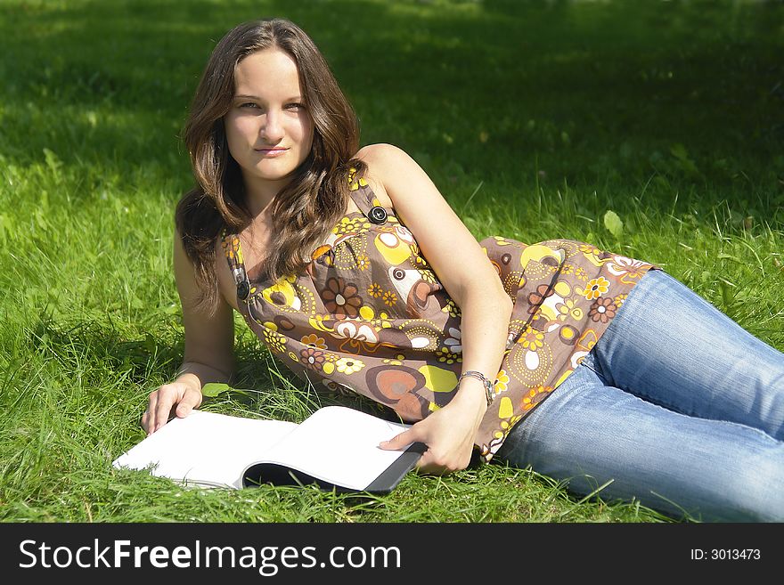 Girl lying on grass with book