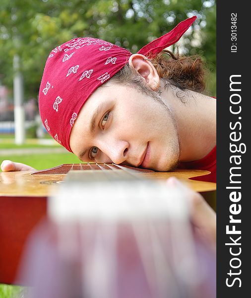 Teenage boy with a guitar on the lawn