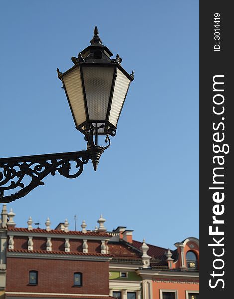 Focus on old-fashioned lamp, on the background old-fashioned buildings. Focus on old-fashioned lamp, on the background old-fashioned buildings