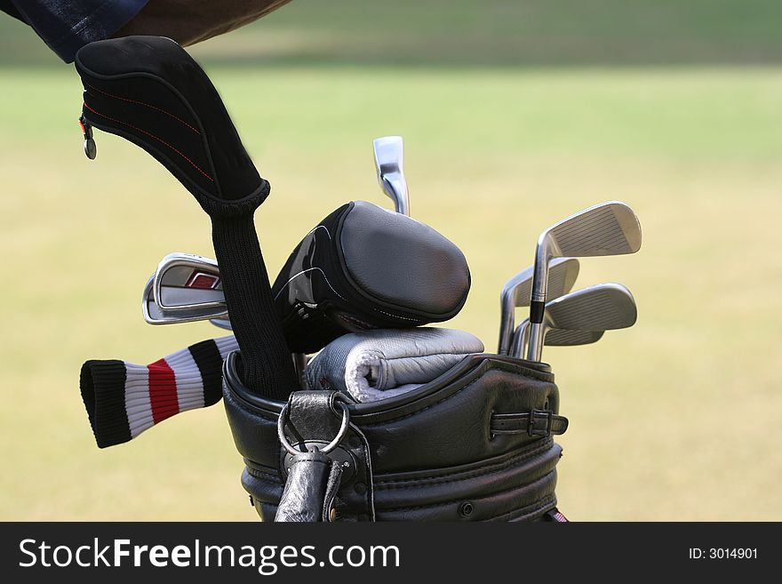 Golf bag and set of clubs on green