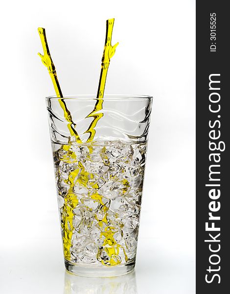 Cold drink with ice and yellow stirring rod isolated on white background