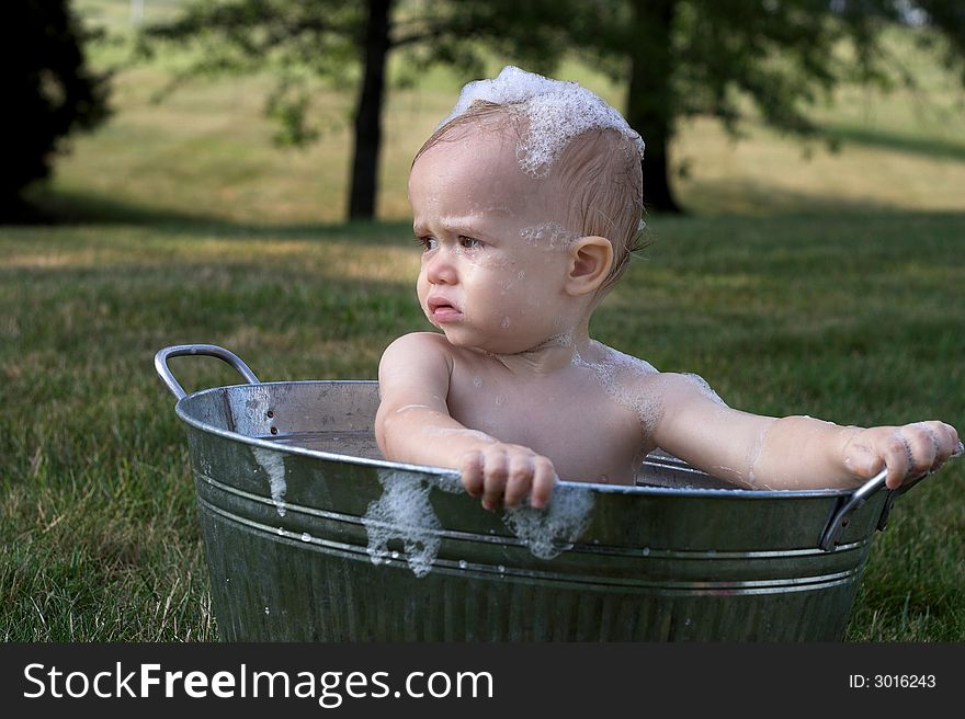 Image of cute toddler sitting in a tub outside. Image of cute toddler sitting in a tub outside