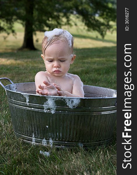 Image of cute toddler sitting in a tub outside. Image of cute toddler sitting in a tub outside