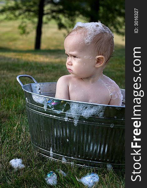Image of cute toddler sitting in a tub outside. Image of cute toddler sitting in a tub outside