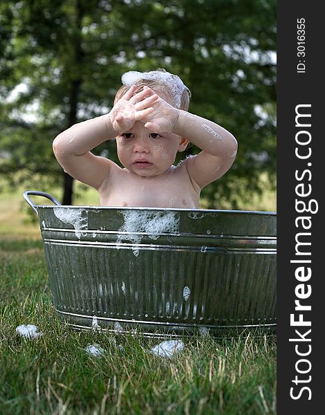 Image of cute toddler sitting in a tub outside. Image of cute toddler sitting in a tub outside