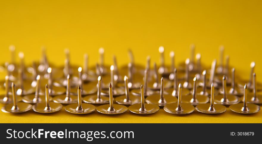 Thumb tacks nickel plated on a yellow background