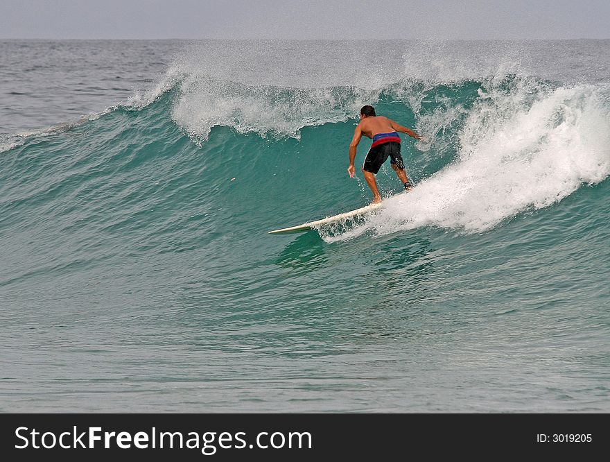 A longboarder takes off on a clean wave in Phuket, Thailand. A longboarder takes off on a clean wave in Phuket, Thailand