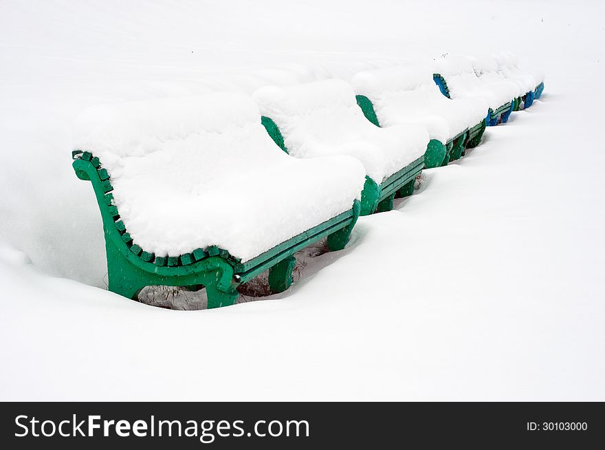 Row of wooden benches, which covered with snow . Row of wooden benches, which covered with snow ..