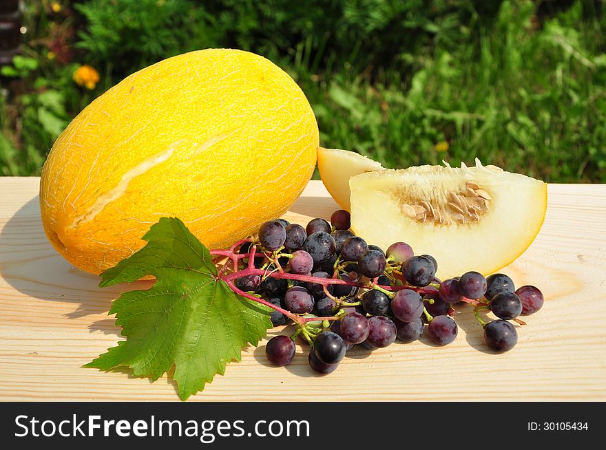 Melon and grapes on a wooden plank. Melon and grapes on a wooden plank.