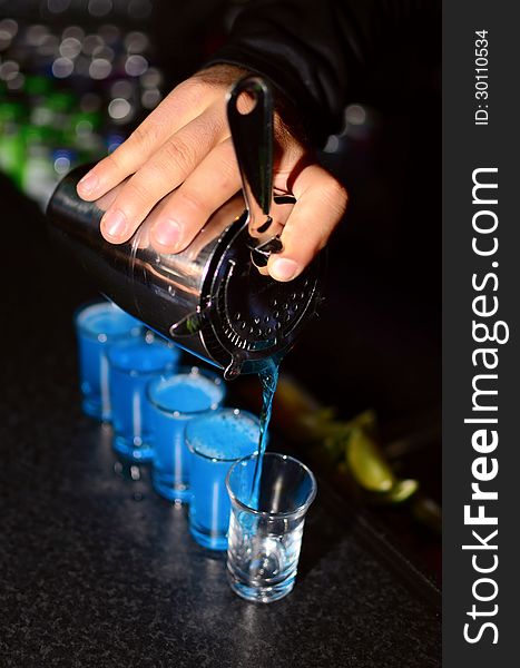 Bartender pours shoots in glasses