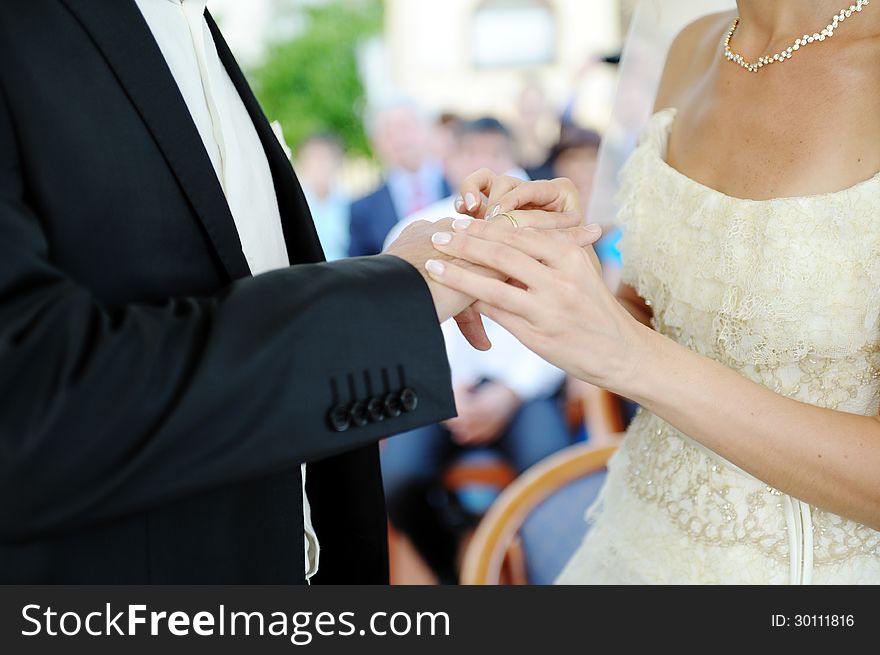 Bride's hand putting a wedding ring on the groom's finger. Bride's hand putting a wedding ring on the groom's finger