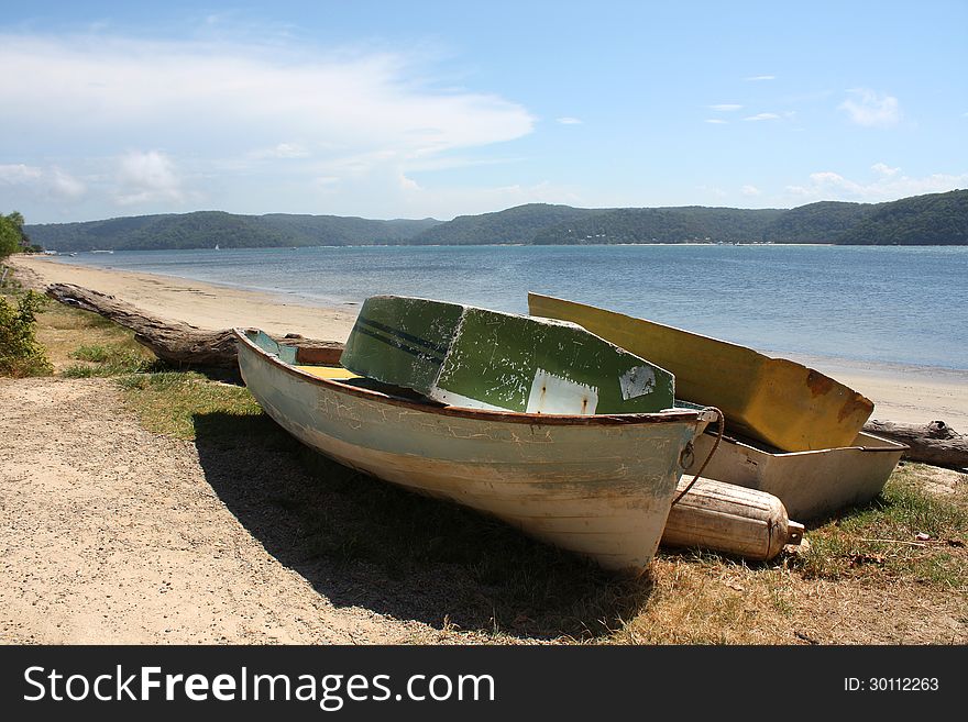 Old simple wooden boats on a tropical beach in australia near sydney with a tranquil ocean and blue sky. Old simple wooden boats on a tropical beach in australia near sydney with a tranquil ocean and blue sky
