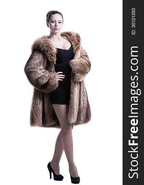 Full length standing in pose woman wearing luxury winter fur coat, black short dress and high-heel shoes. Shot in studio. Isolated on white. Full length standing in pose woman wearing luxury winter fur coat, black short dress and high-heel shoes. Shot in studio. Isolated on white.