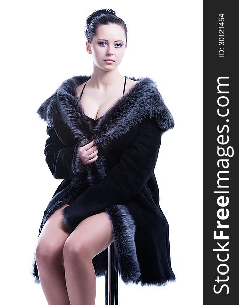 Beautiful woman with decollete in luxury fur coat sitting