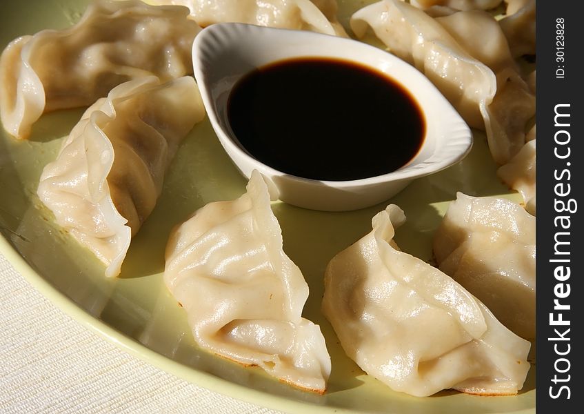 Chinese dumpling with soy sauce on dish.
