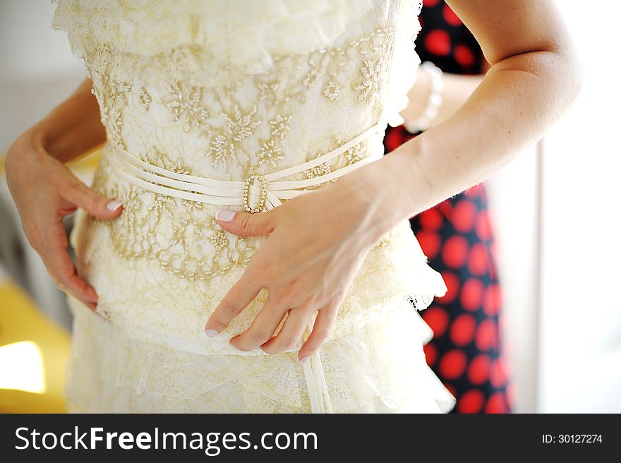 Bridesmaid helping bride to dress