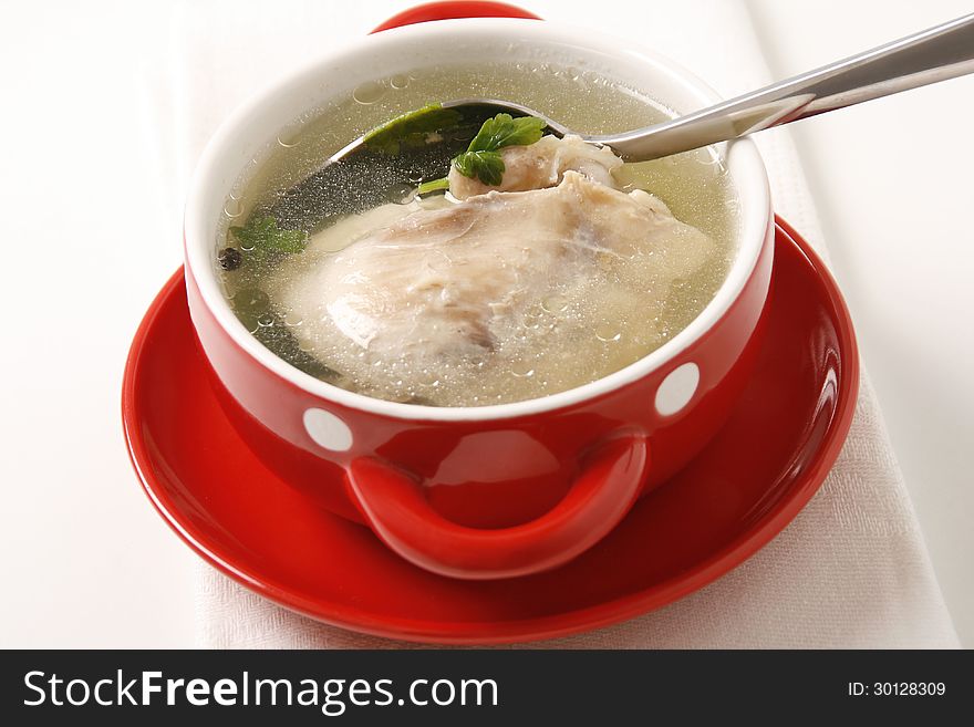 A bowl of chicken broth on table. A bowl of chicken broth on table.