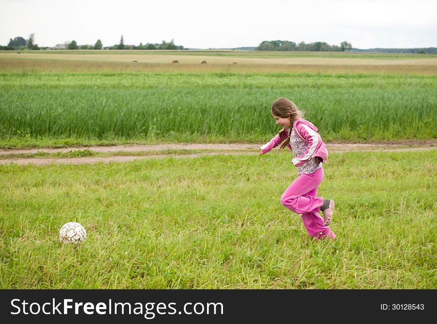 Girl with ball running in a meadow