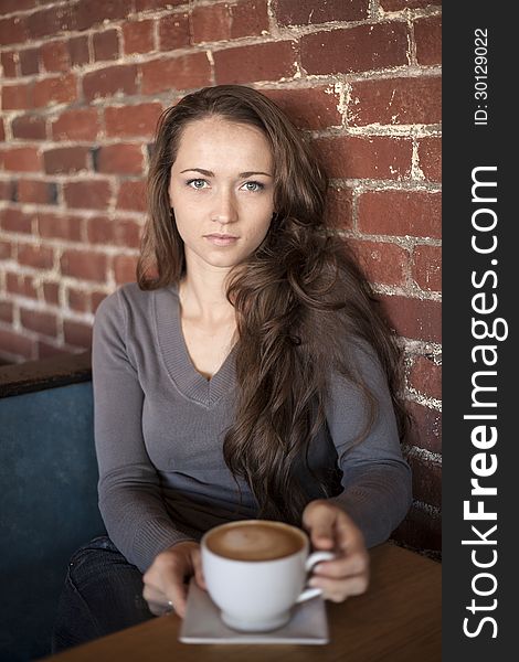 Portrait of a young woman with a white coffee cup looking directly at the camera. Portrait of a young woman with a white coffee cup looking directly at the camera