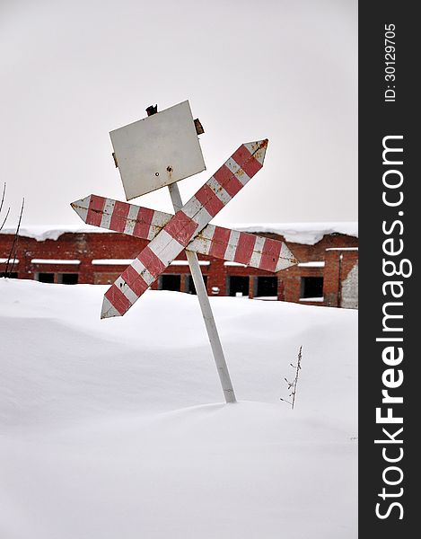 Abandoned building and the old road sign in the snow.
