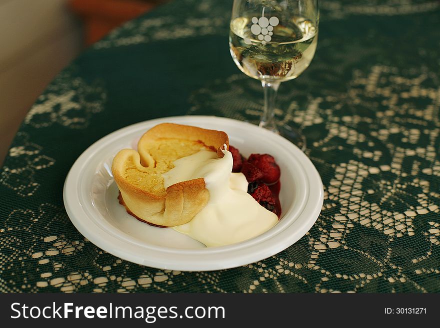 Custard Tart dessert served with thick cream and Raspberries and a glass of white wine