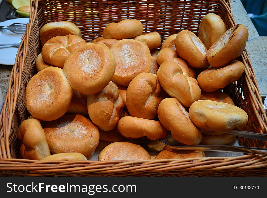 Lot of freshly baked buns in a wicker basket on a stone table. Lot of freshly baked buns in a wicker basket on a stone table