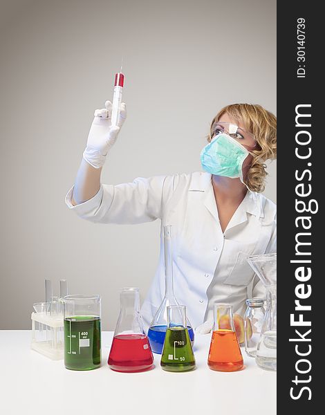 Portrait of female laboratory staff dealing with test syringe. isolated over gray background. vertical shot. Portrait of female laboratory staff dealing with test syringe. isolated over gray background. vertical shot