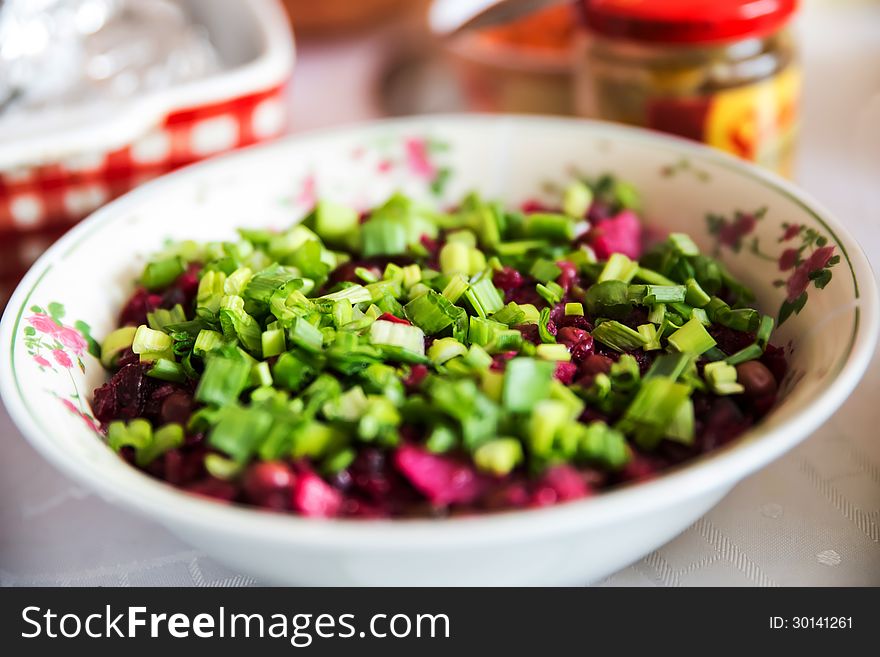 Homemade healthy beetroot salad with fresh young onions on top in the bowl. On the blurred kitchen background. Homemade healthy beetroot salad with fresh young onions on top in the bowl. On the blurred kitchen background.