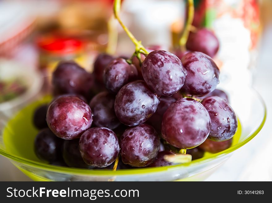 Close up of cluster of washed fresh red grapes in a bowl. On blurred background. Close up of cluster of washed fresh red grapes in a bowl. On blurred background.
