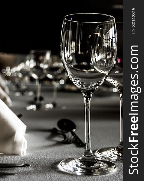 Black and white shot of a table setting with wineglasses, white napkins and silwerware on white tablecloth. Black and white shot of a table setting with wineglasses, white napkins and silwerware on white tablecloth.