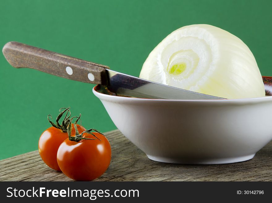 Tomatoes on the table and onion in a bowl, green background. Tomatoes on the table and onion in a bowl, green background