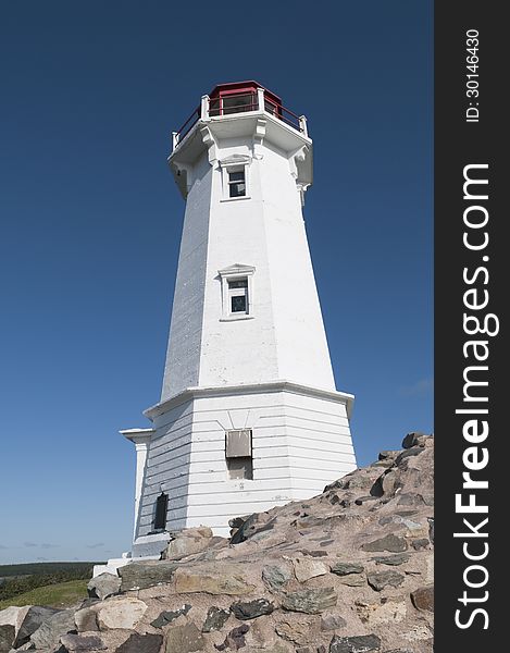 Louisbourg lighthouse with stone support in the foreground - intense blue sky good for copy space