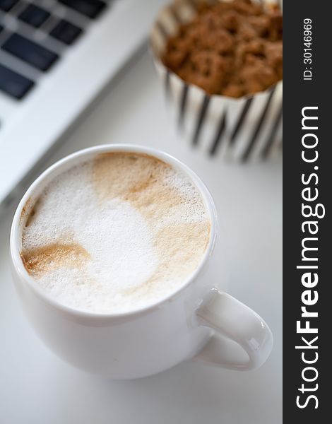 A cup of coffee and a laptop on a white desk