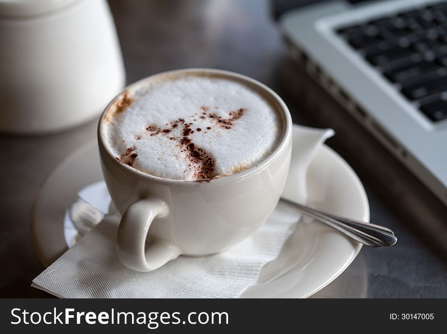 A cup of coffee and a laptop on a desk