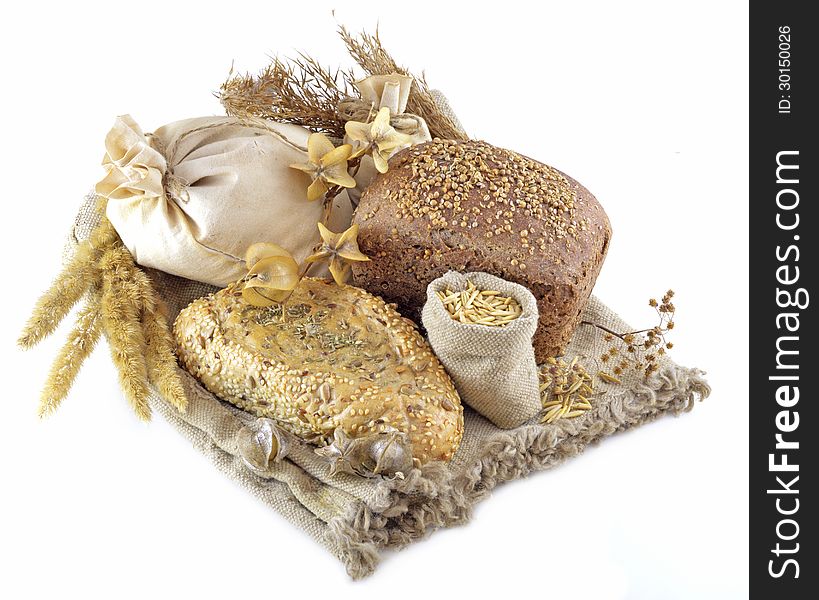 Different types of bread with herbs on hessian fabric isolated. Different types of bread with herbs on hessian fabric isolated