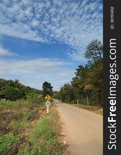 Country road in a rural area with a traffic sign (speed limit 30 km/hr) in Thailand