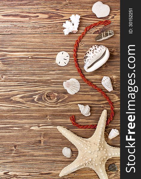 Starfish, shells, stones and coral beads on a brown wooden background. Starfish, shells, stones and coral beads on a brown wooden background