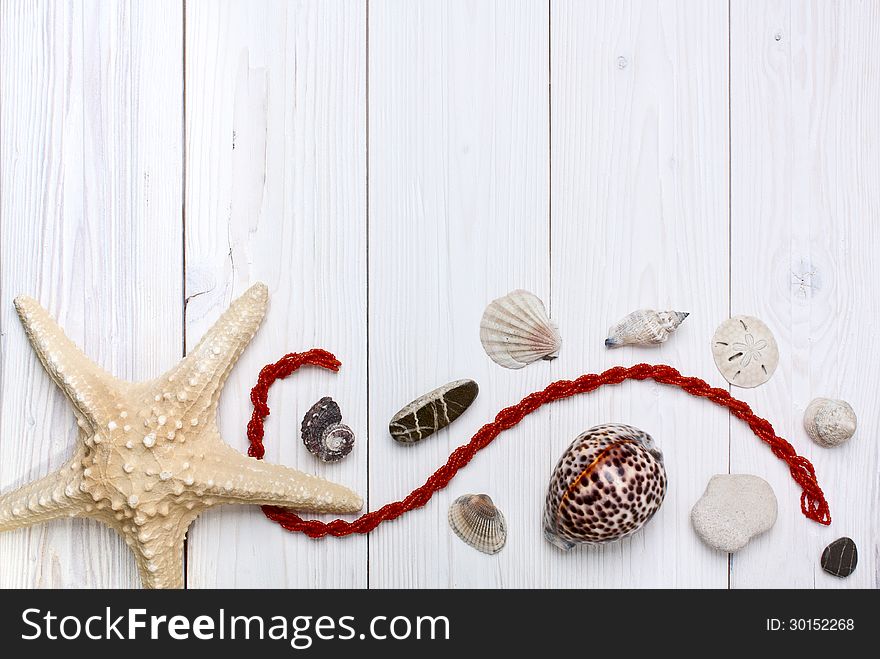 Starfish, shells, stones and coral beads on a white wooden background. Starfish, shells, stones and coral beads on a white wooden background