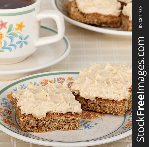 Two peanut butter bars on a plate with a cup of coffee