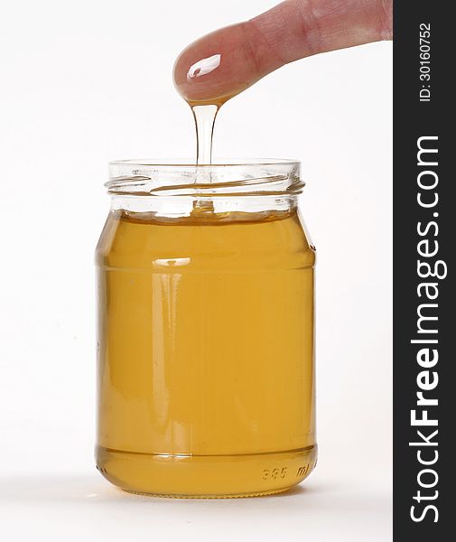 Honey pot and a finger on white background. Honey pot and a finger on white background