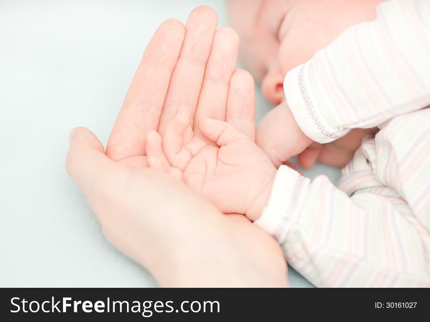 Little baby hands and hand of the mother. This image has attached release.