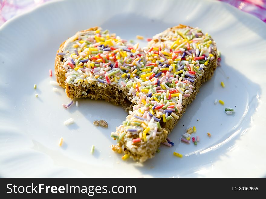 A heart-shaped slice of bread with sprinkles on it.