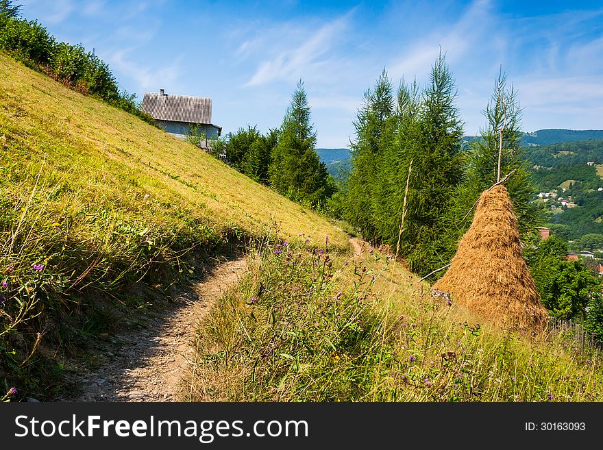 Wooden stick fence in village in mountains with blue sky, green grass and path in good weather time. Wooden stick fence in village in mountains with blue sky, green grass and path in good weather time